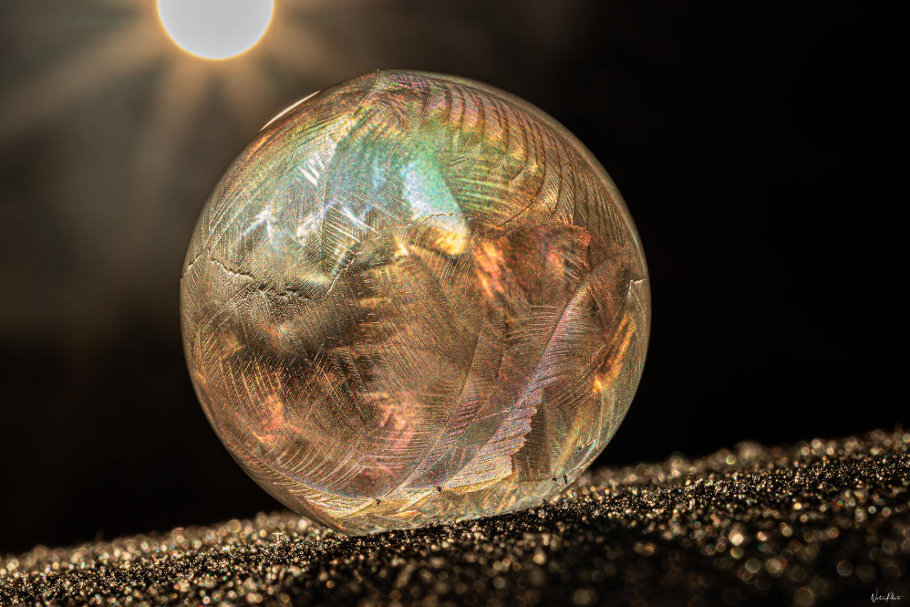 Bulle de savon gelée, couverte de cristaux de givre, au soleil