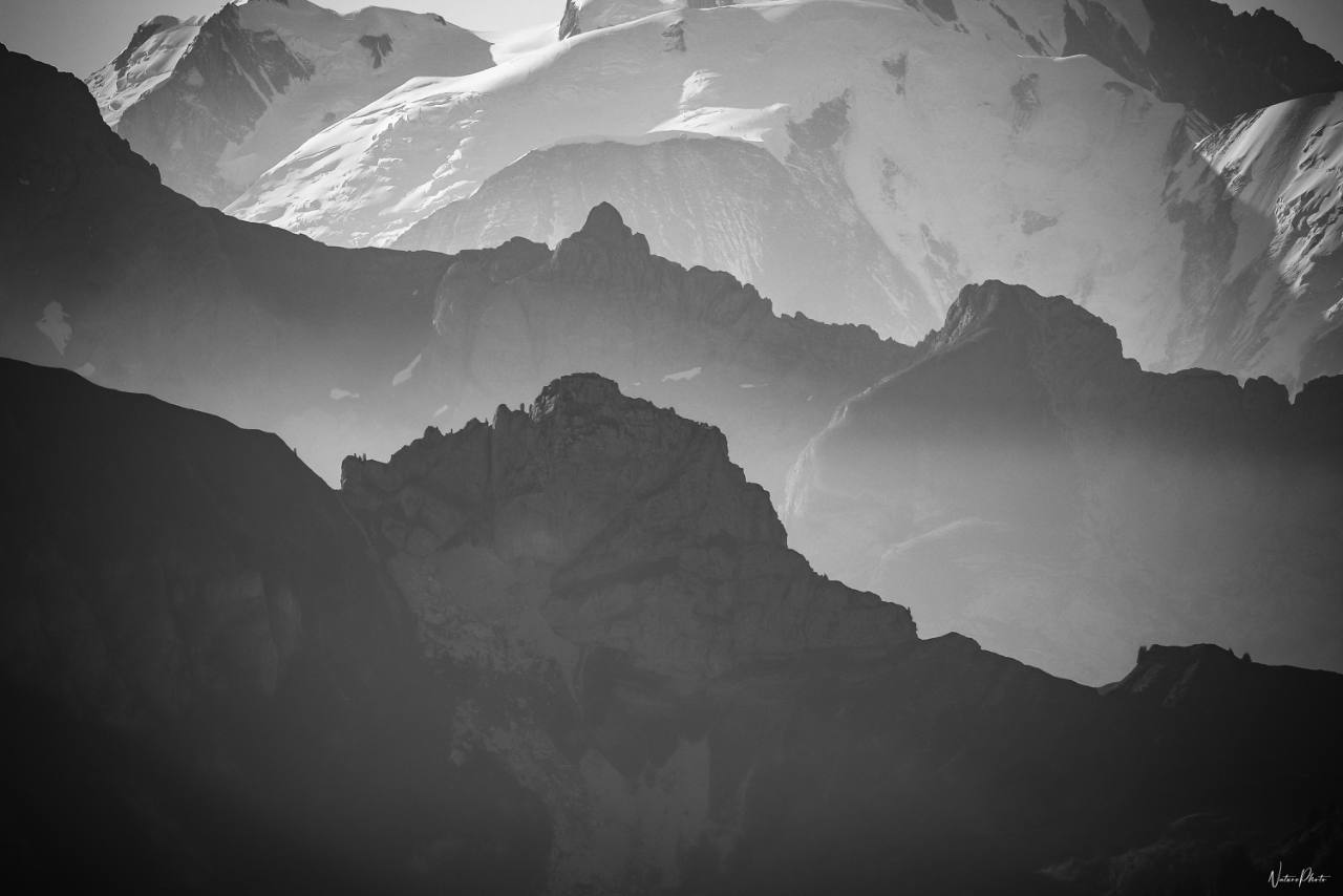 Crêtes de montagne qui se superposent dans la brume, en noir et blanc