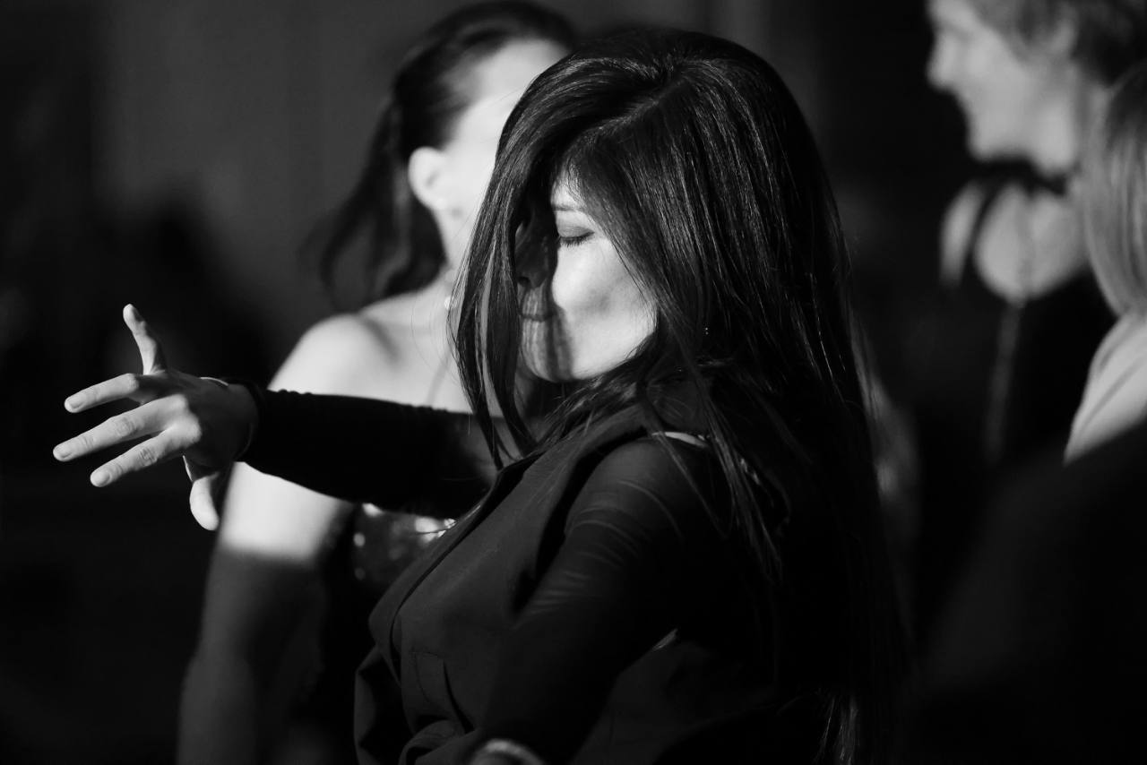 Une femme danse les yeux fermés pendant une soirée, en noir et blanc