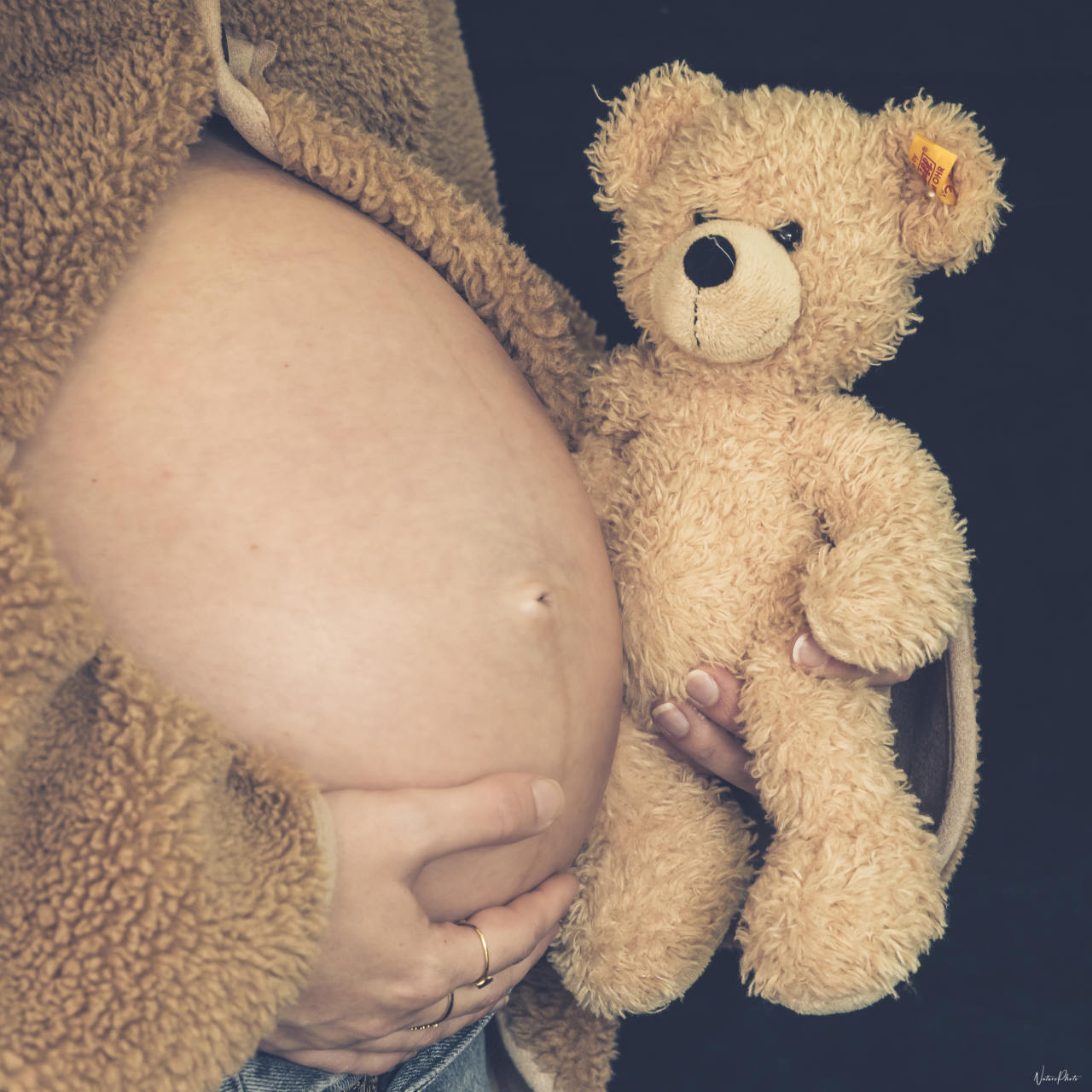 Ventre rond d’une future maman qui tient un ours en peluche