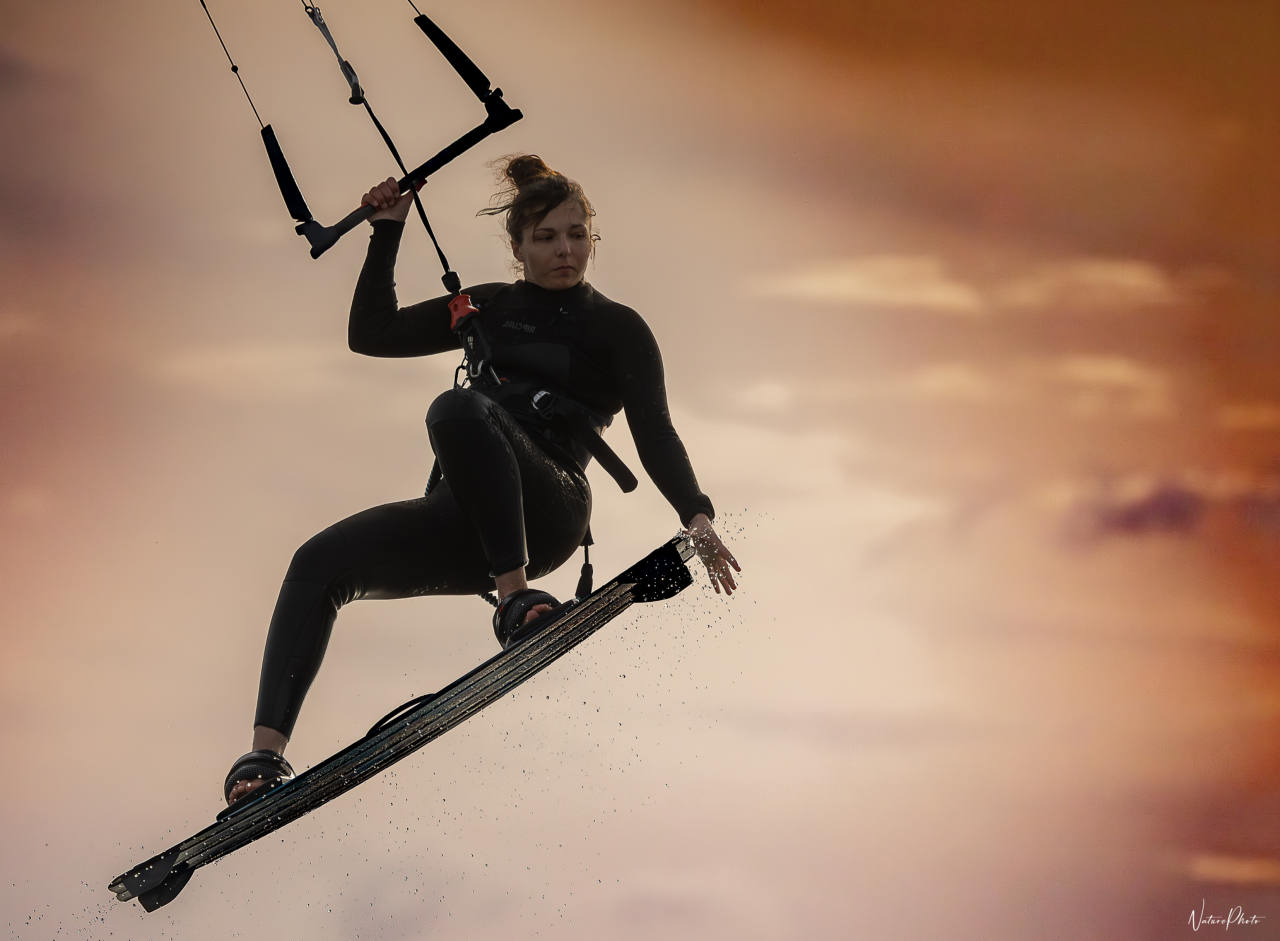 Kitesurfeuse en l’air au soleil couchant