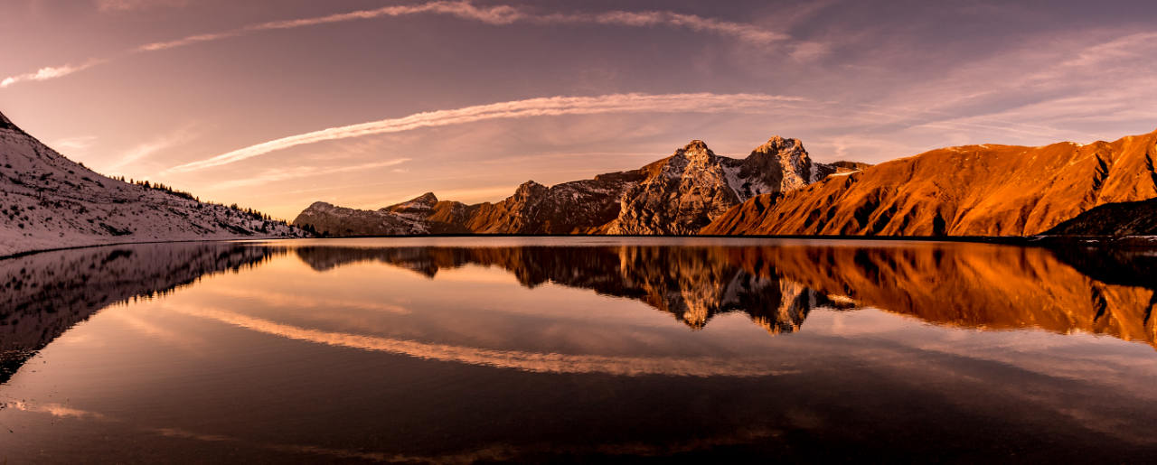 Montagnes rougies par le soleil du soir, reflétées dans un lac