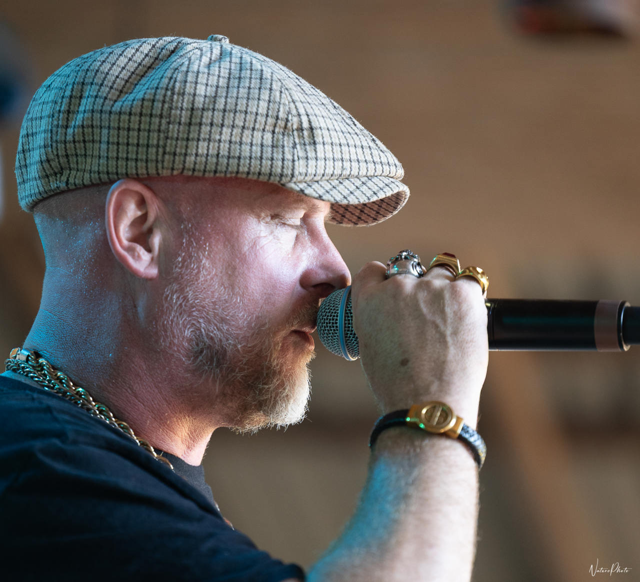 Musicien à casquette et lunettes de soleil, les mains autour du micro