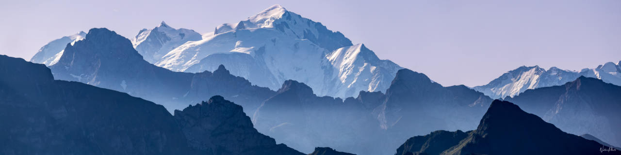 Panorama de sommets enneigés au-dessus de crêtes bleutées