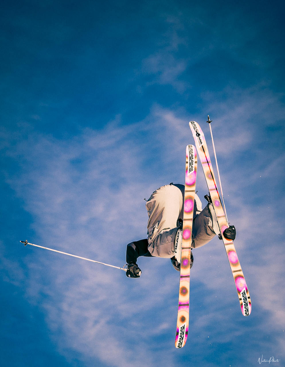 Skieur la tête en bas en plein saut, sur fond de ciel bleu