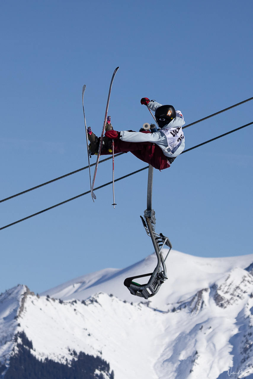 Skieur qui saute au-dessus d’un câble de télésiège, montagnes enneigées au fond